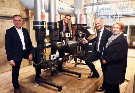 Am Fernwärmenetz. Gabriele Luczak-Schwarz, Erste Bürgermeisterin von Karlsruhe und Aufsichtsratsvorsitzende der Stadtwerke Karlsruhe, Rheinstettens Oberbürgermeister Sebastian Schrempp (2.v.l.) und die Geschäftsführer der Stadtwerke Karlsruhe Michael Homann (l.) und Dr. Olaf Heil (2.v.r.) vor der Fernwärmeübergabestation in der Schwarzwaldschule Rheinstetten.