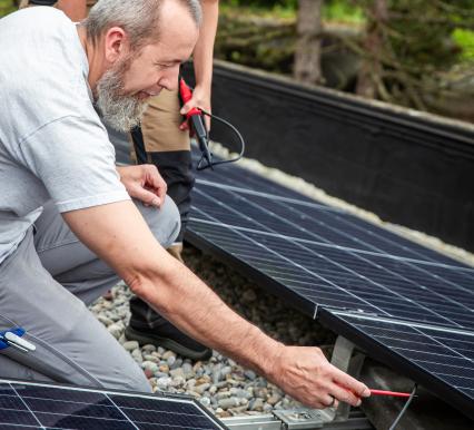 Mann und Frau inspizieren Solarmodule im Freien.