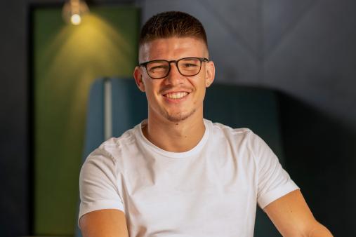 Mann lächelt an einem Tisch im Büro.