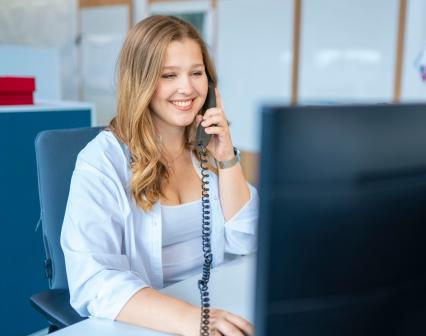 Lächelnde Frau telefoniert am Schreibtisch.