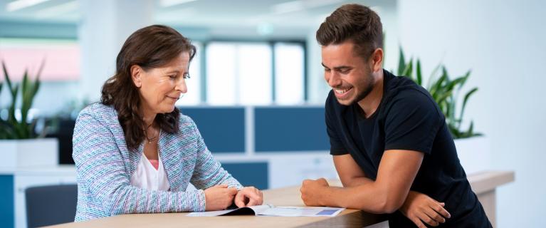 Frau und Mann besprechen ein Dokument am Empfangstresen.